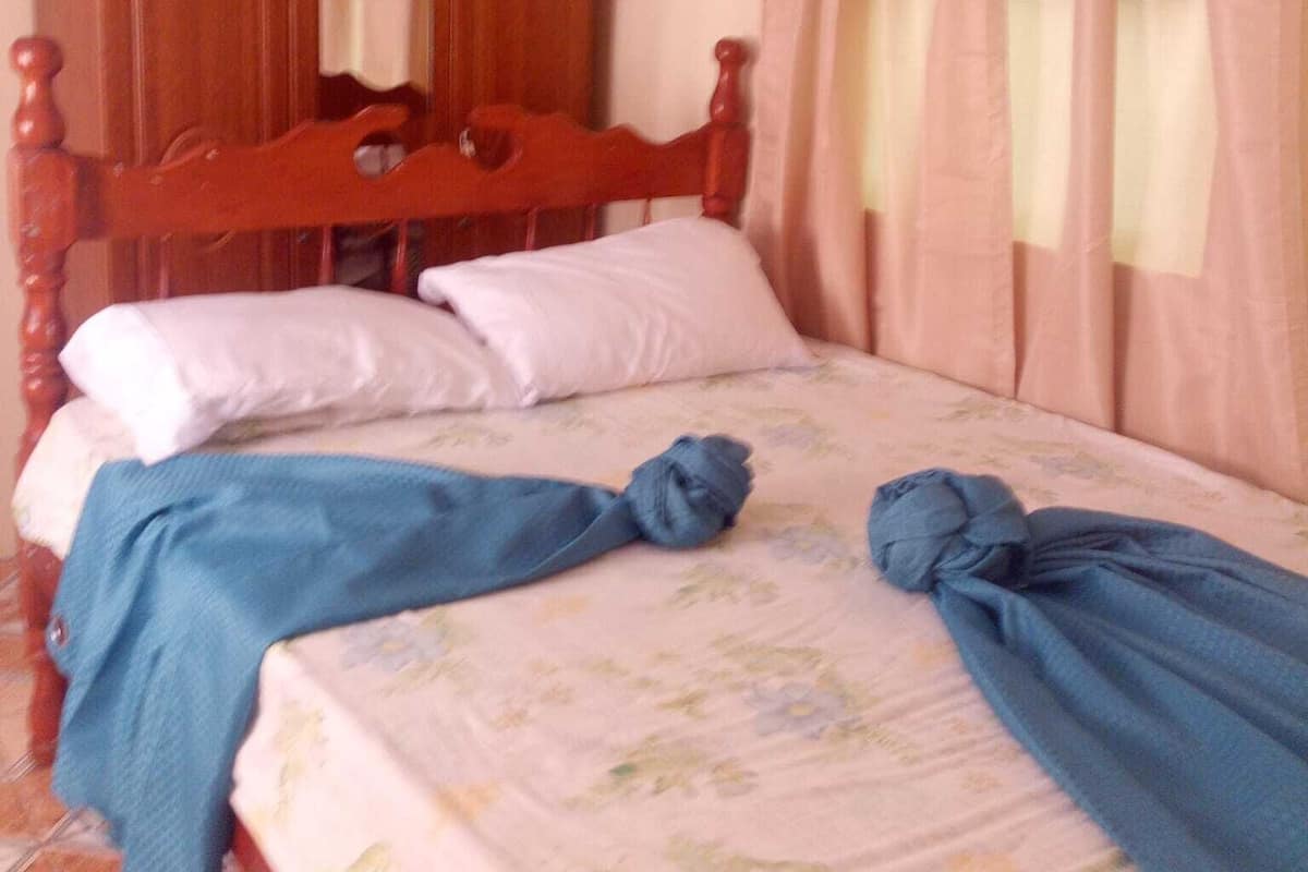A single bed with a floral bedspread, a wooden headboard, and a mirror above it.