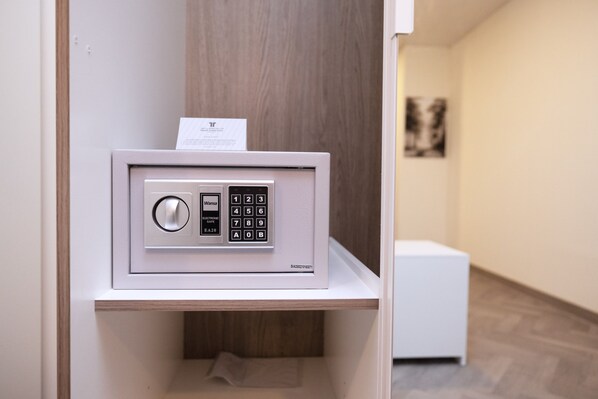 A secure electronic safe on a white shelf in a hallway.