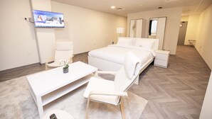 Une chambre d’hôtel équipée d’un lit, d’un bureau, d’une chaise, d’un téléviseur fixé au mur et d’un miroir.
