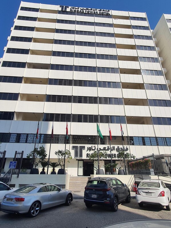 A multi-story hotel with a modern facade, balconies, and a sign indicating it is the Rigg Tower Hotel.