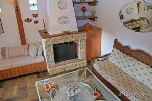 A living room with a fireplace, a sofa, a coffee table, and decorative plates on the wall. - Private property with outdoor pool , cosy spaces and beautiful garden (Kato Archanes)