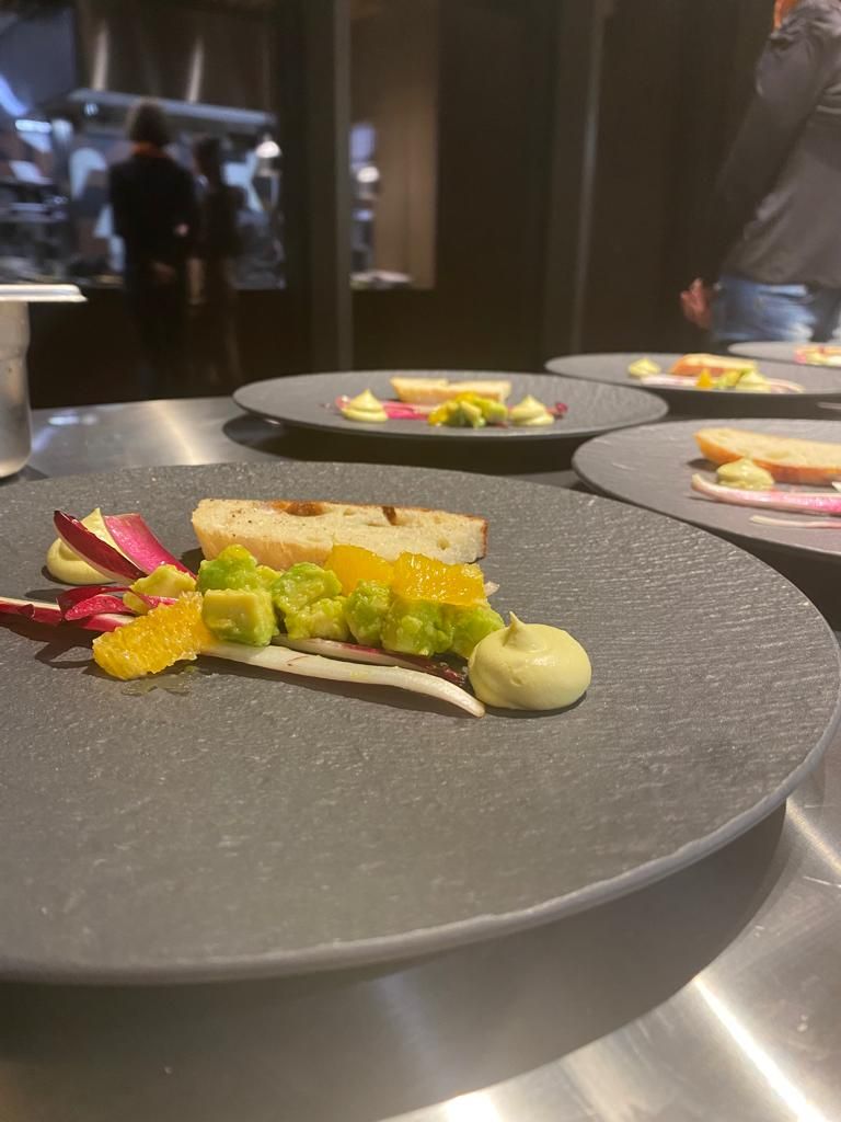 Une table à manger sur laquelle on trouve une variété d’aliments, notamment du pain, un avocat et un petit récipient contenant de la sauce.