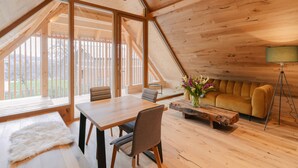 A modern loft with a wooden interior, large windows, a dining area, and a sofa. - Pira Hotel (Postojna)