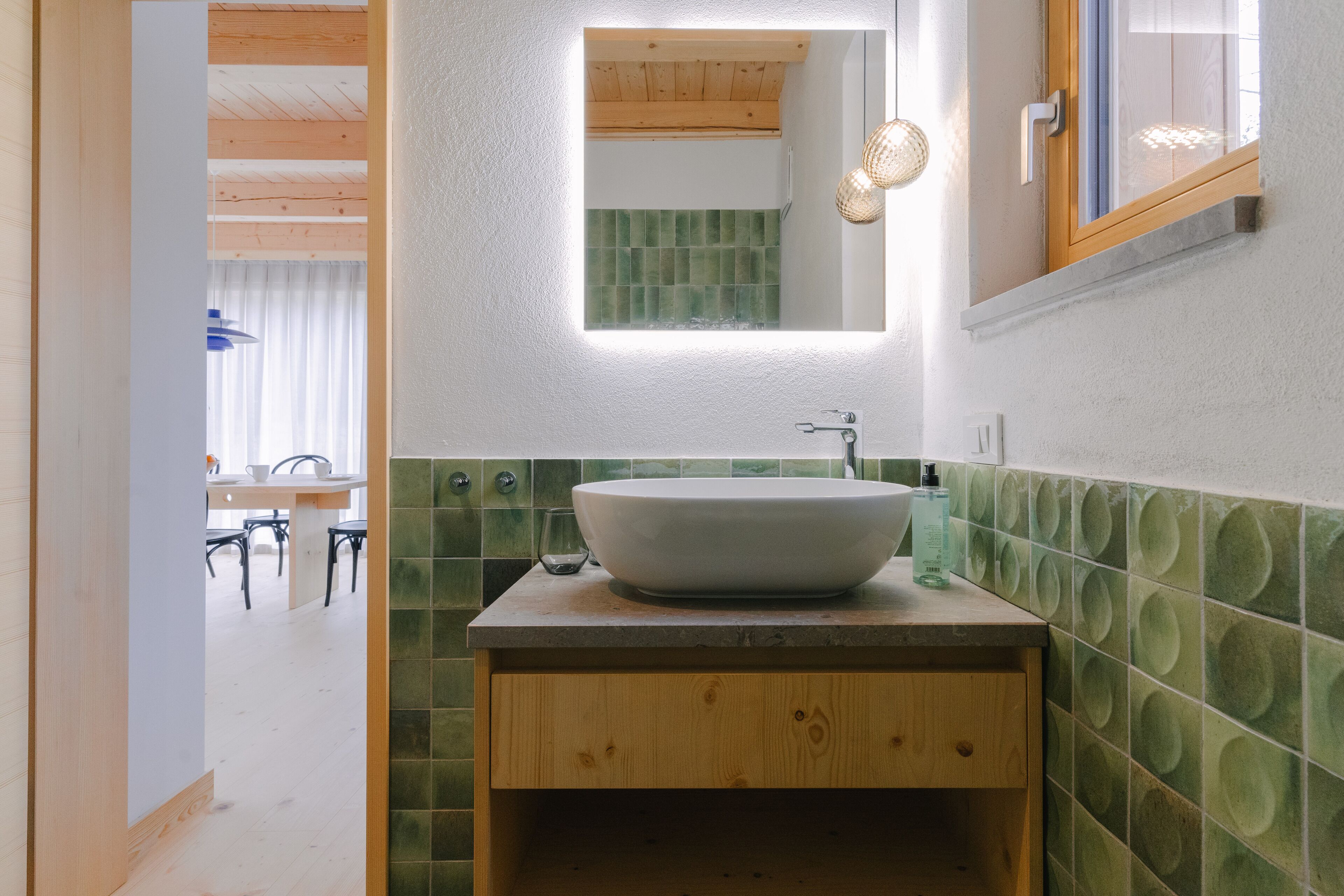 A bathroom with a large vessel sink, wooden cabinetry, and a mirror above it.