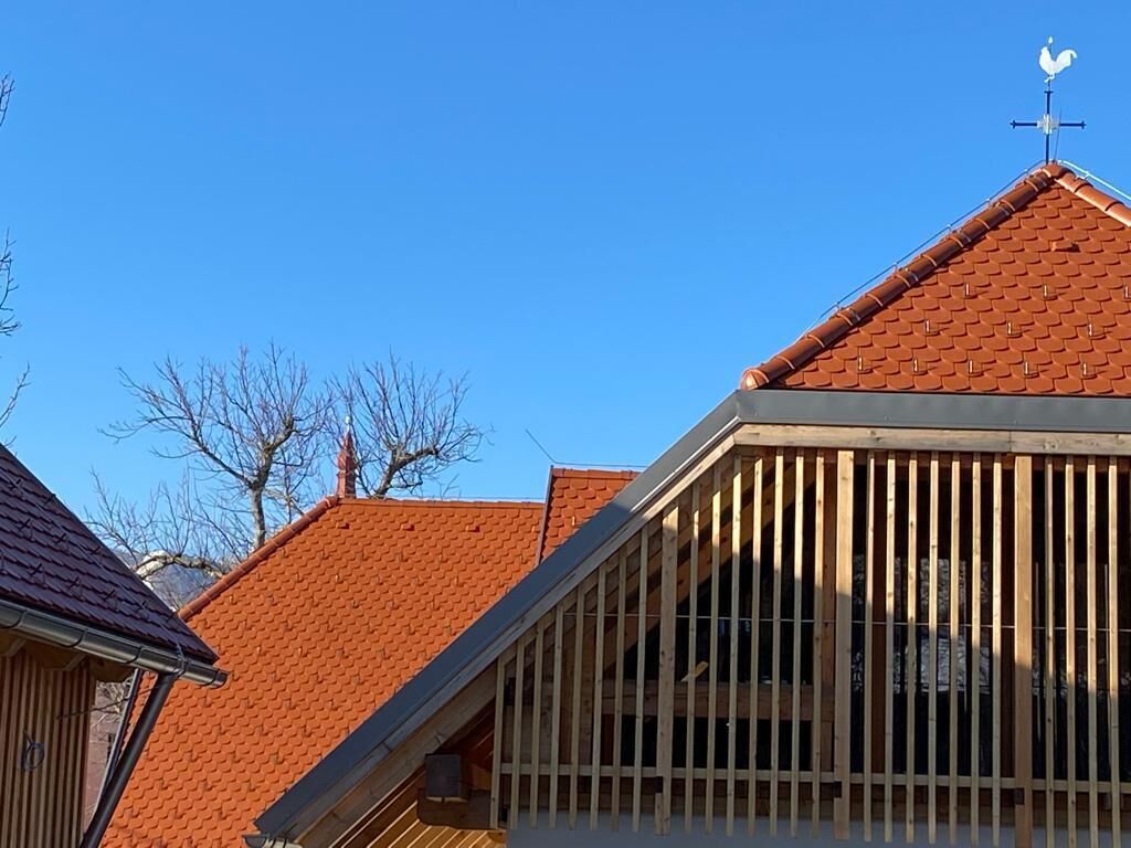 A building with a sloped roof, wooden beams, and a weather vane.