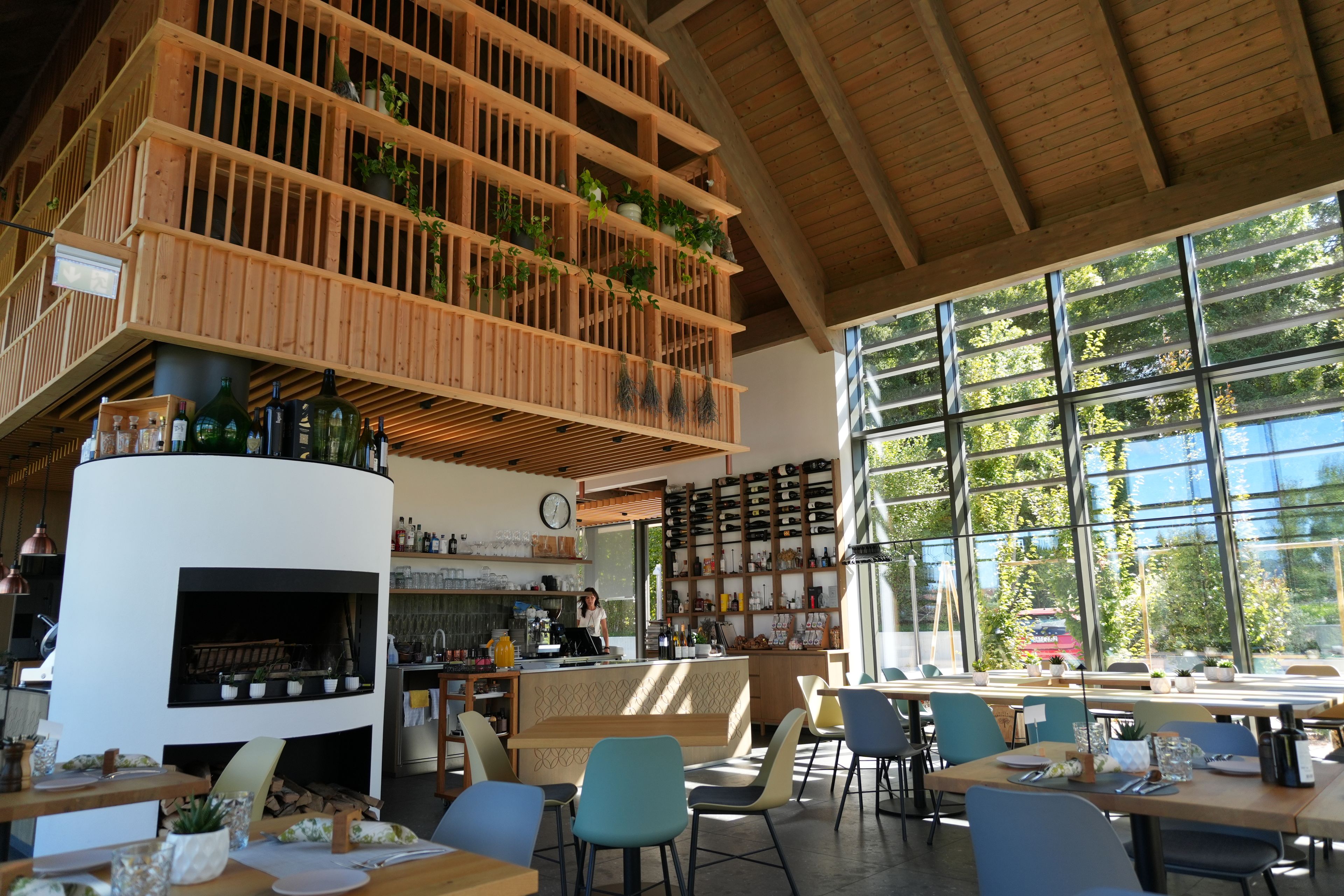 An interior with a wooden ceiling, a bar area with bottles, and a seating area with tables and chairs.