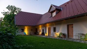 A house with a sloped roof, a covered patio area, and a well-maintained lawn.