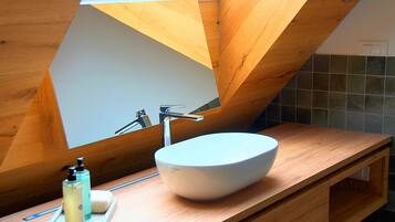 A modern bathroom with a skylight, a white vessel sink, and wooden cabinetry.