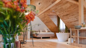 A modern bedroom with a sloped ceiling, a large bathtub, and a wooden floor. - Pira Hotel (Postojna)