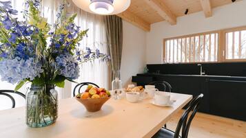A dining area with a wooden table, a vase of flowers, and a bowl of fruit.