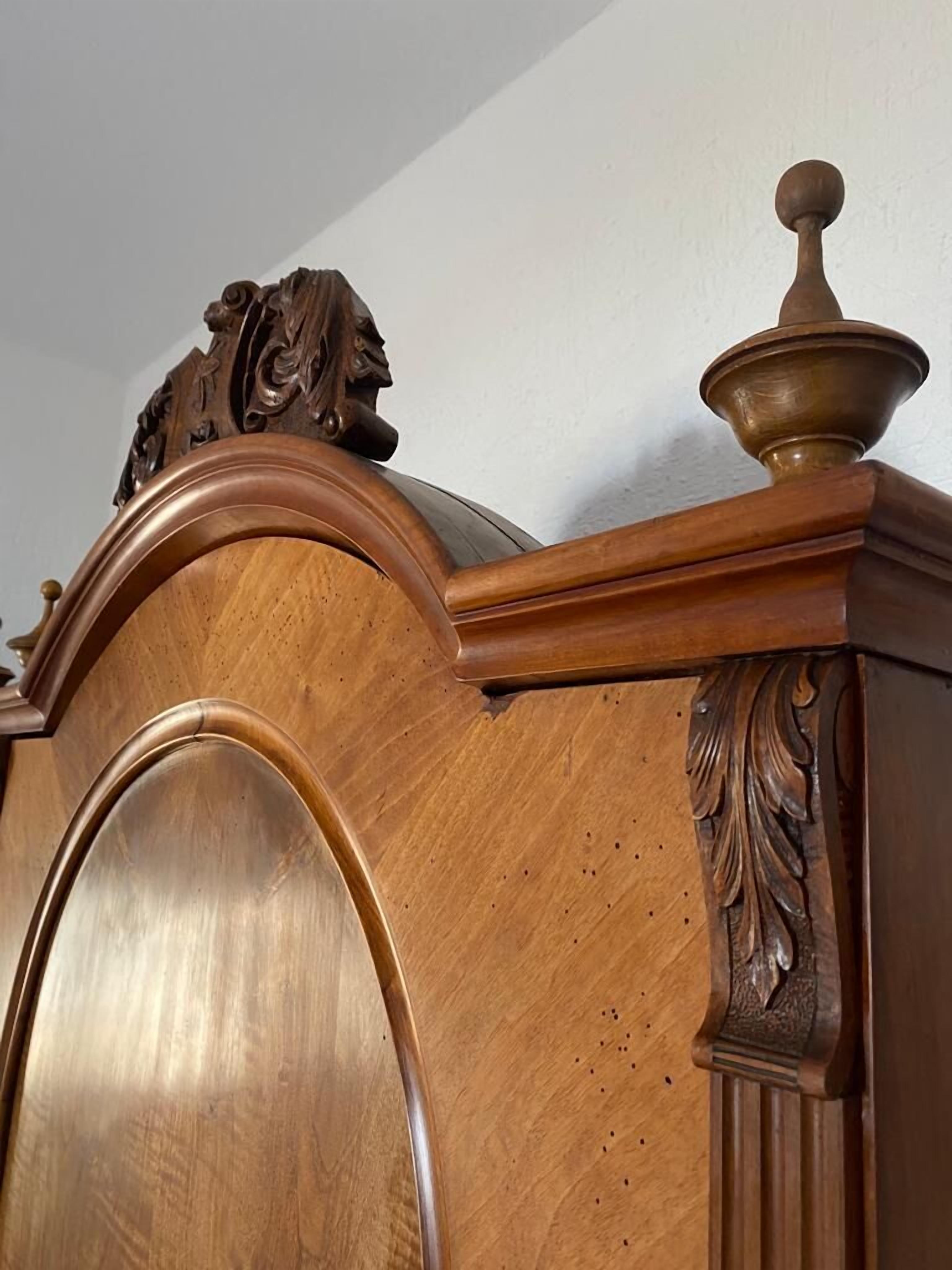 Een houten kast met een decoratieve bovenkant en een grote, gebogen deur.