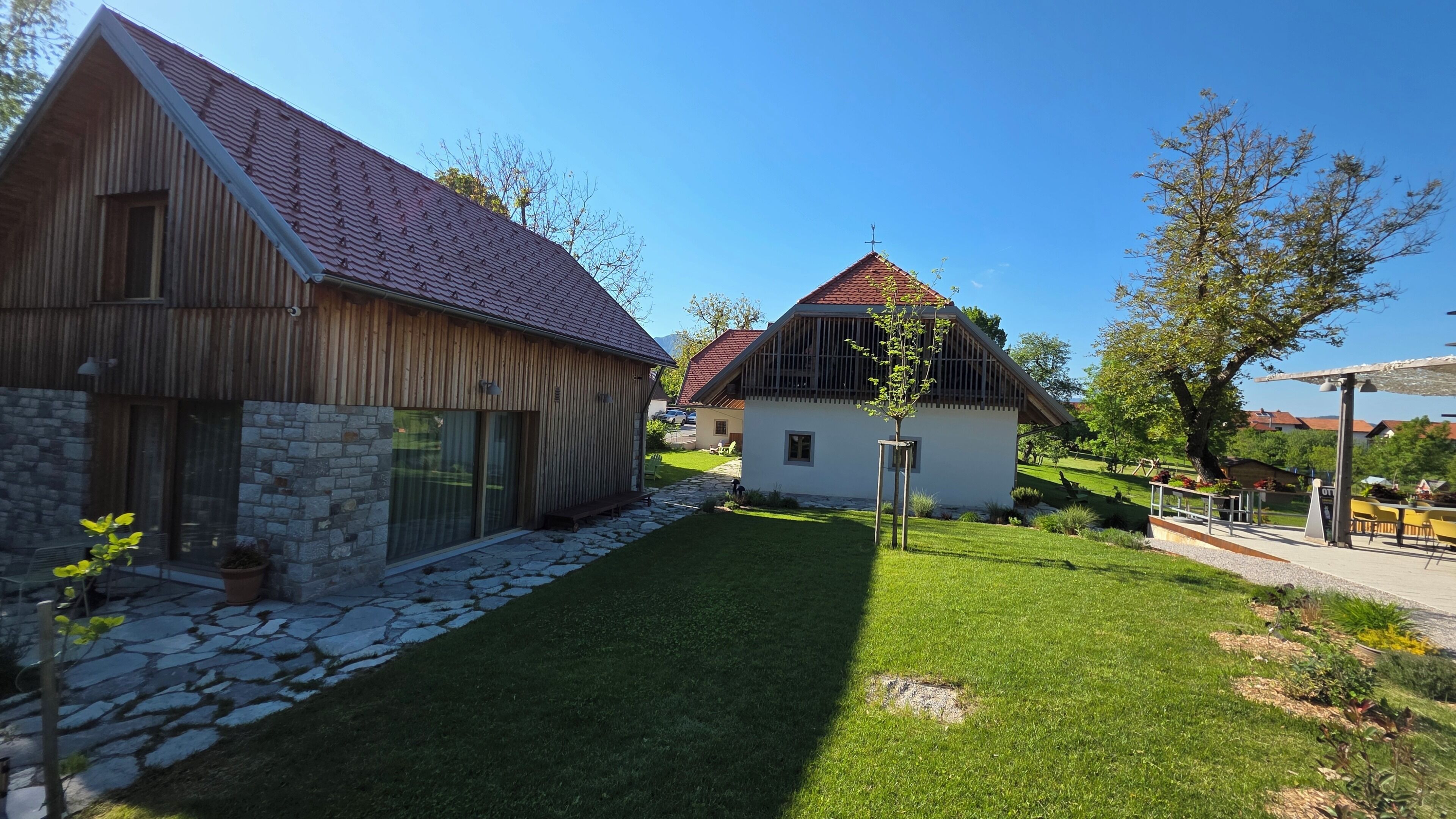 En lantlig fastighet med en stenmur, trähus och en välskött gräsmatta.