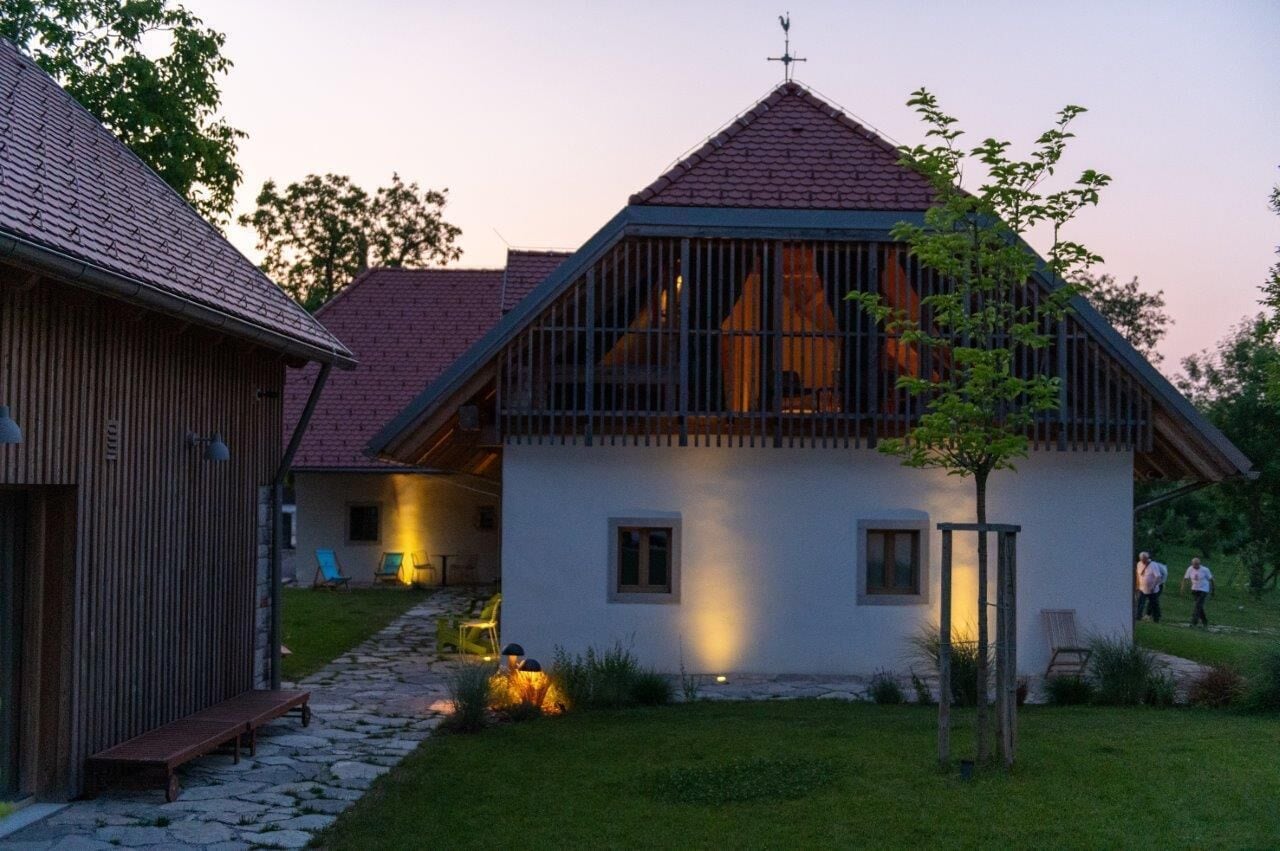 A traditional house with a sloped roof, a wooden exterior, and a stone pathway leading to the entrance.