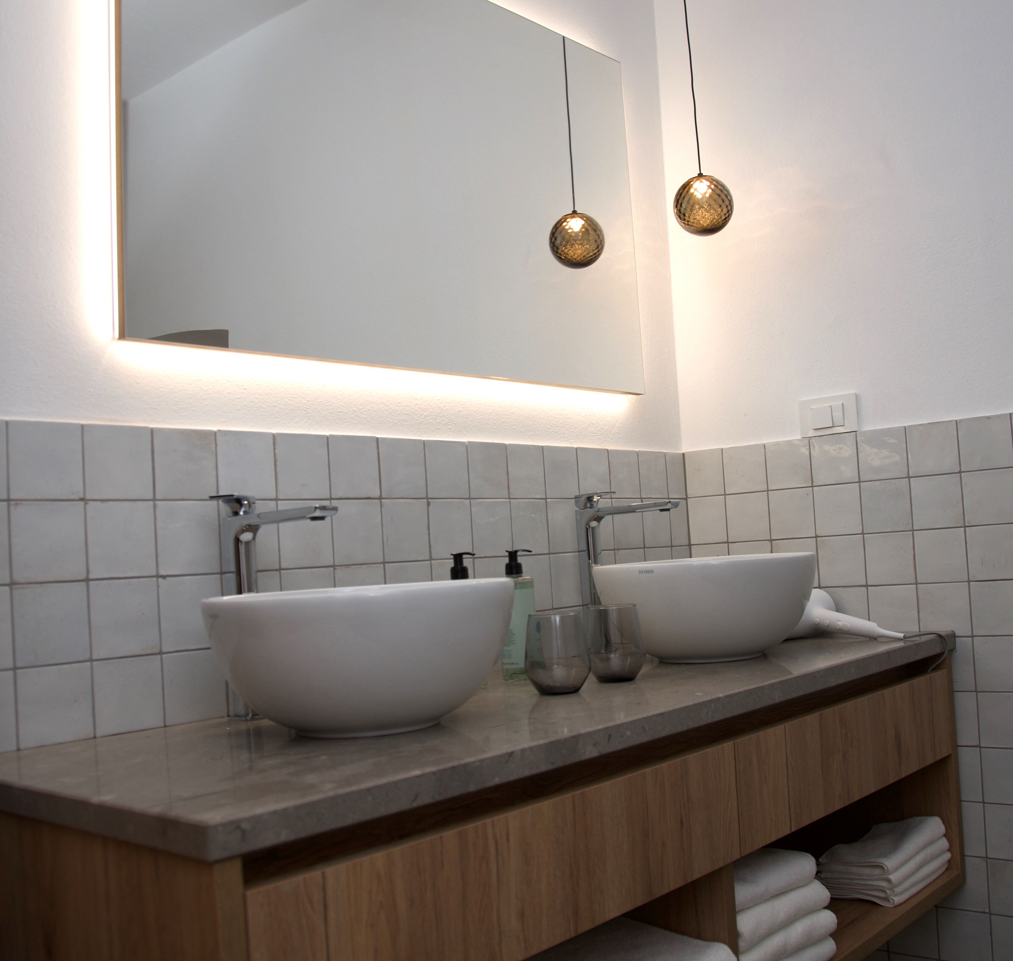 A modern bathroom with two white sinks, a wooden vanity, and a large mirror.