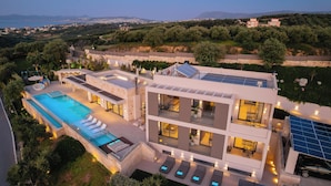 Un immeuble moderne à plusieurs étages, doté d’une piscine sur le toit, de panneaux solaires et offrant une vue sur le paysage environnant.