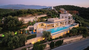 Une villa moderne dotée d’une piscine, d’un espace salon extérieur et offrant une vue sur les collines environnantes.