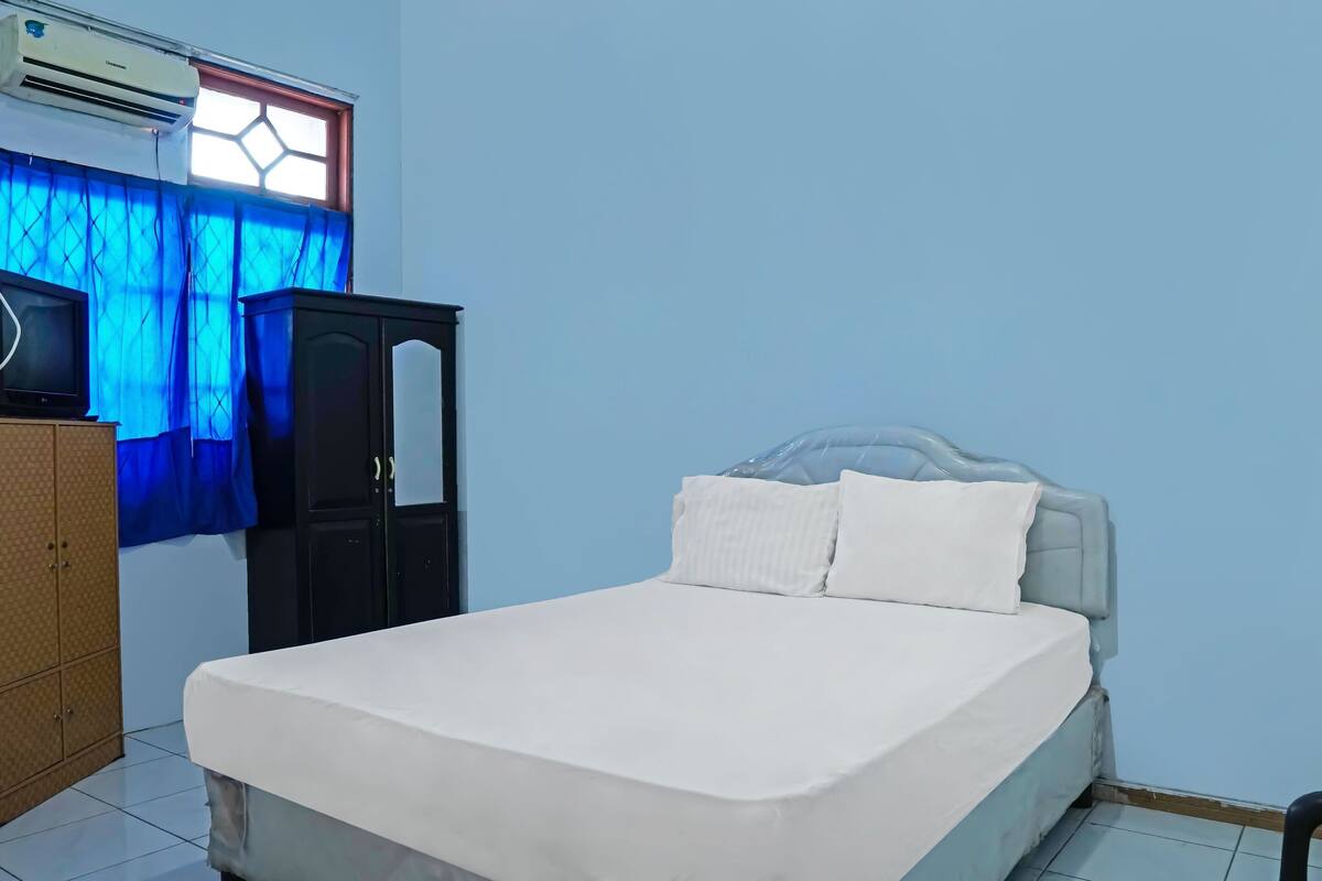 A bedroom with a bed, a wardrobe, and a window with curtains.