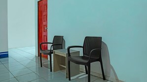 Una stanza con due sedie di plastica nera, un tavolino e una porta rossa.