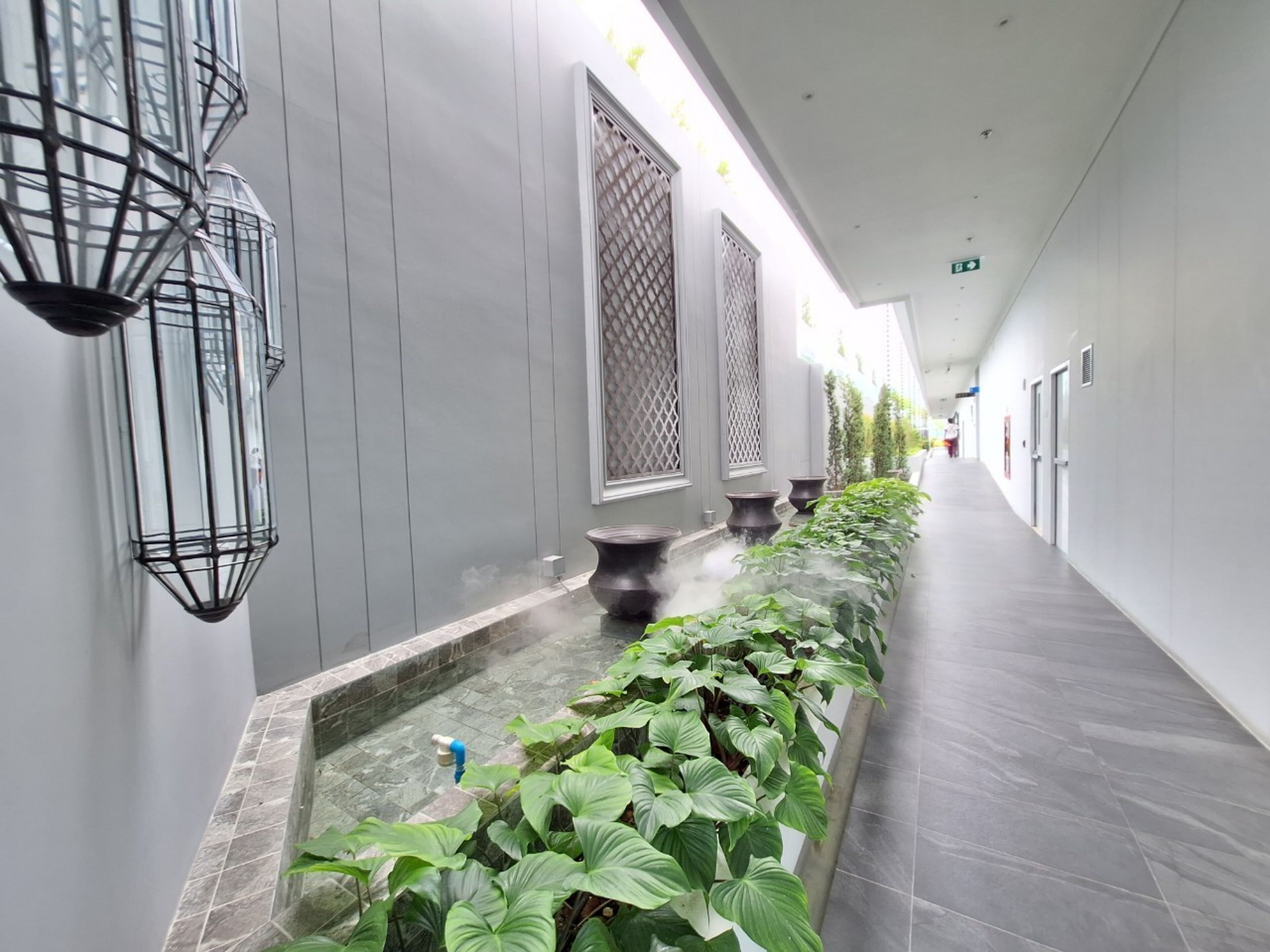 Een gang met een fontein, potplanten en een betegelde vloer.