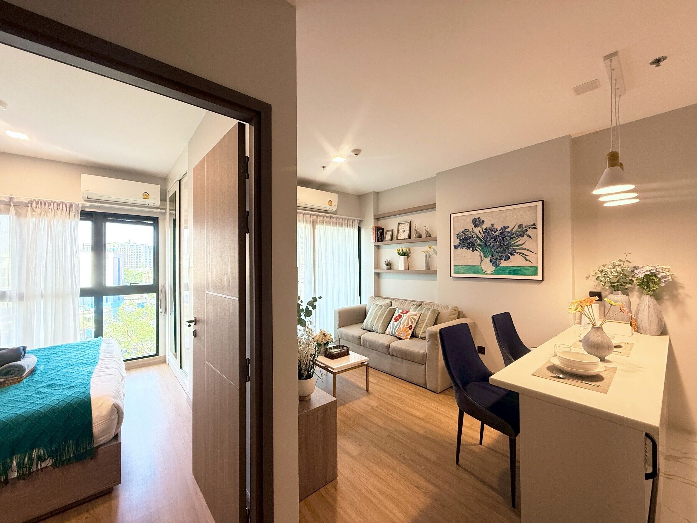 A modern apartment with a bed, a sofa, a dining area, and a kitchen.