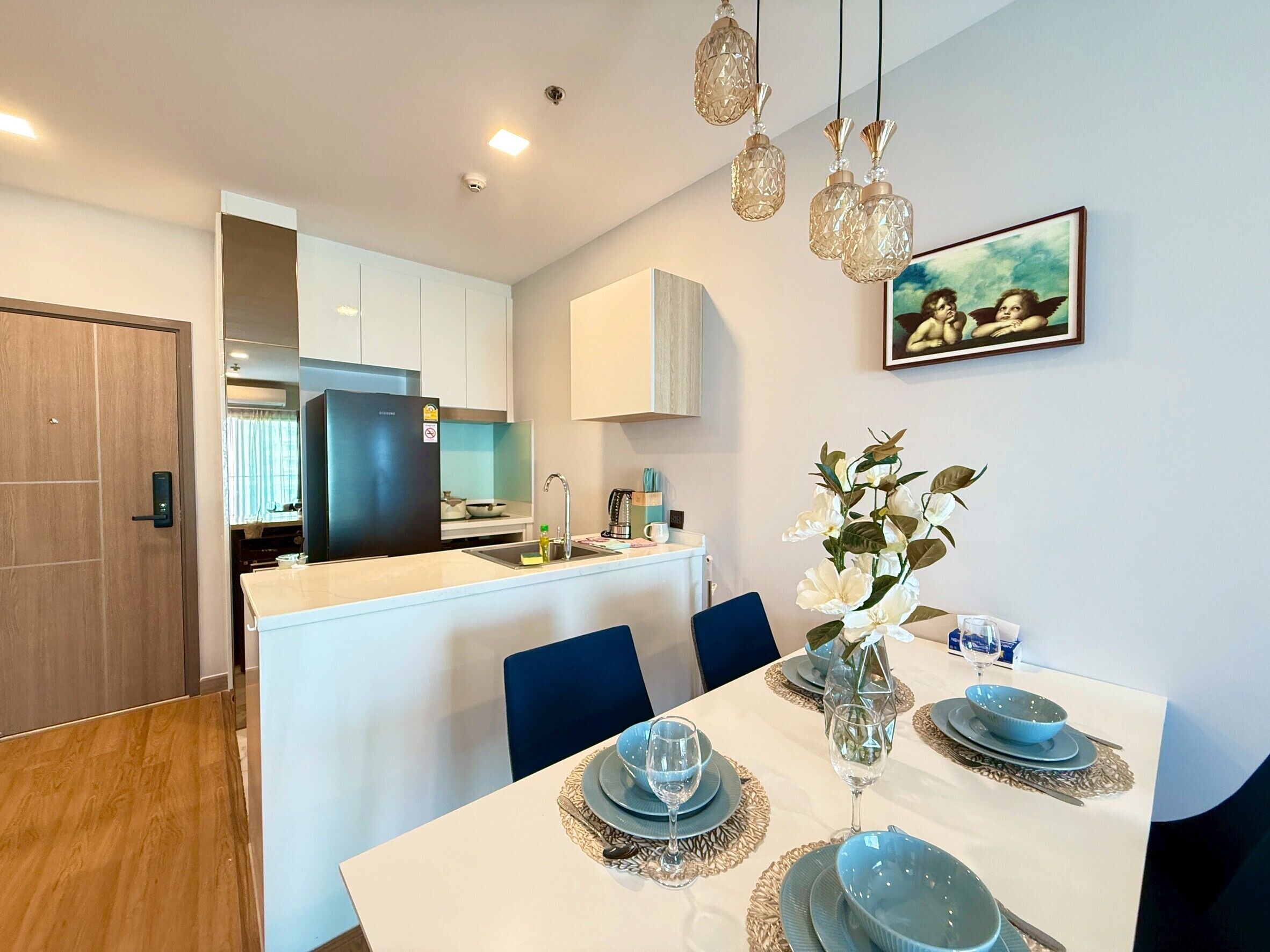 A modern kitchen with white cabinets, a black refrigerator, and a dining area with a white table set for two.