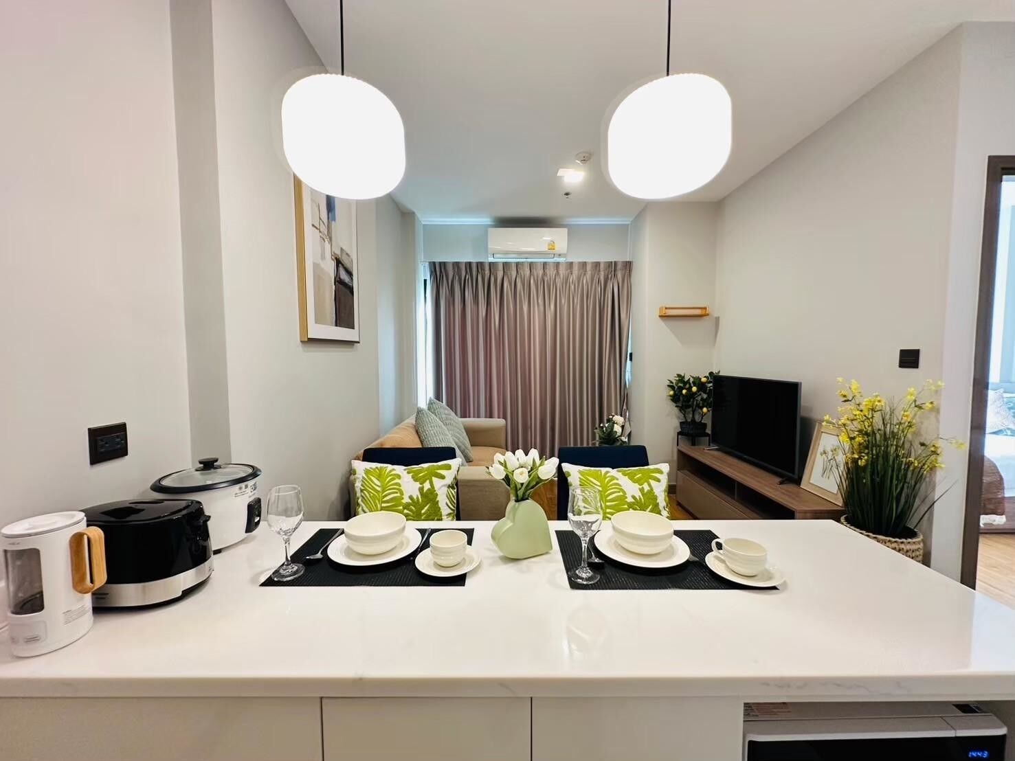 Uma cozinha moderna com área de jantar, destacando uma ilha central com cafeteira, cozido lento e televisão.