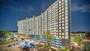 A high-rise hotel with multiple balconies, a parking area, and a construction site nearby. - Astra Sky River Chiang Mai By Fang (Chiang Mai)