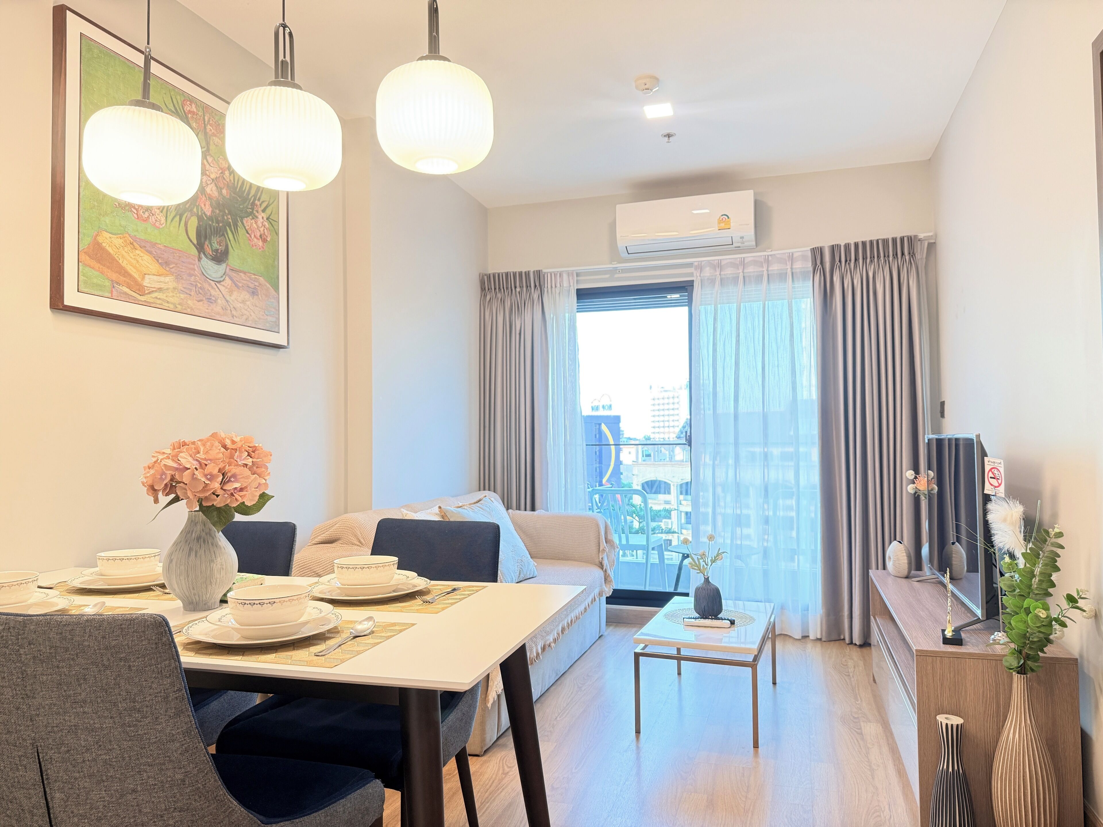 Una sala de estar moderna con una mesa de comedor, un sofá, una mesa de centro y un amplio ventanal con cortinas.
