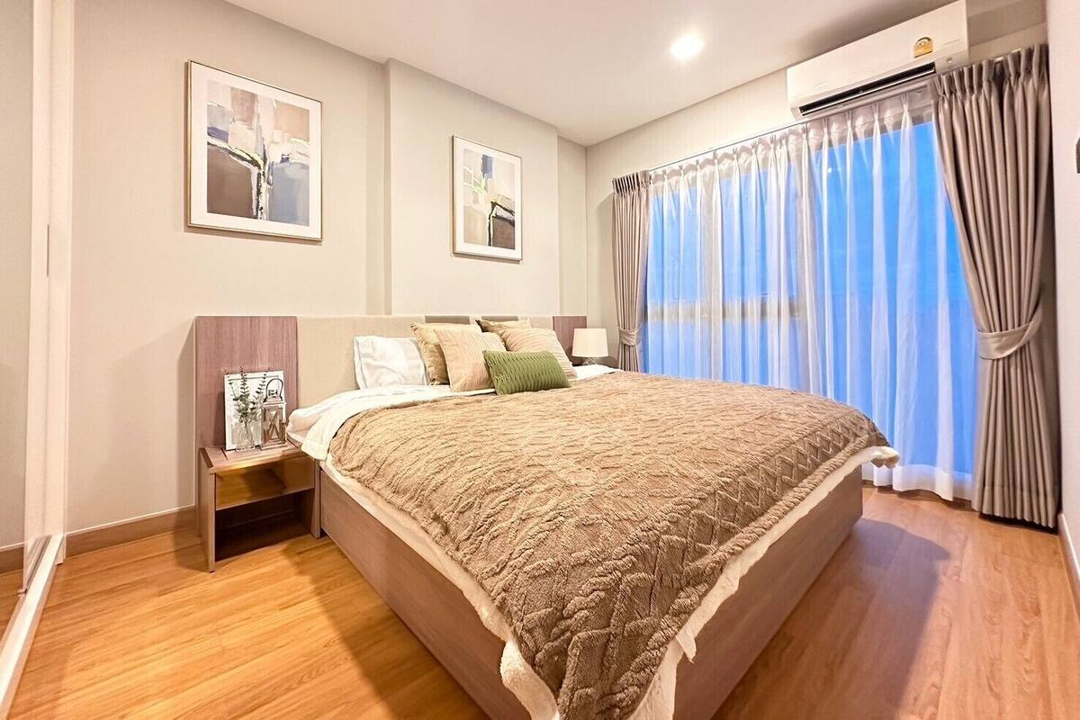 A modern hotel room with a large bed, a nightstand, and a wall-mounted air conditioning unit.