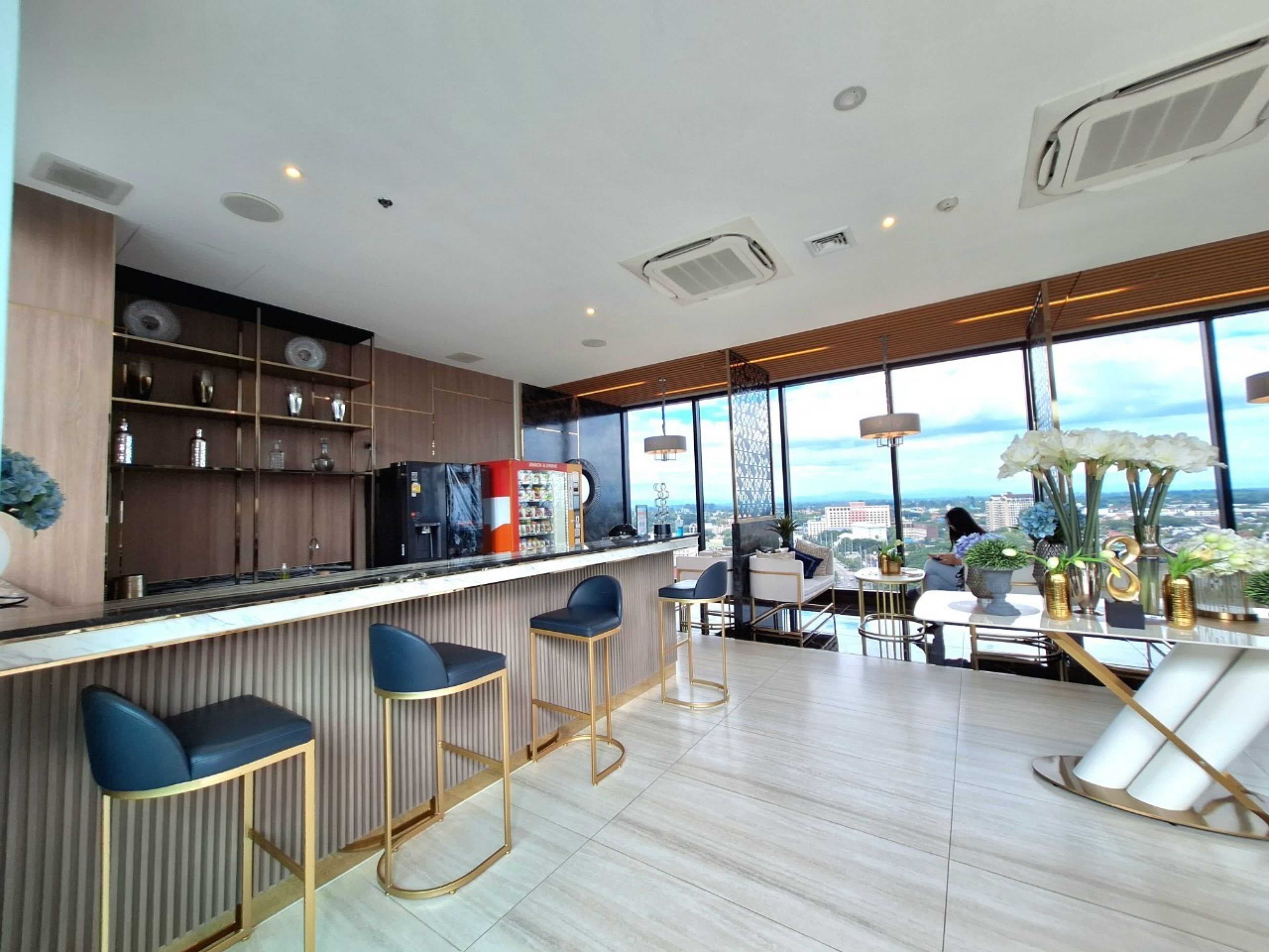 A modern bar area with a city view, bar stools, and a seating area with a table and chairs.