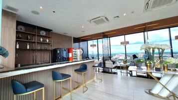 A modern bar area with a city view, bar stools, and a seating area with a table and chairs.