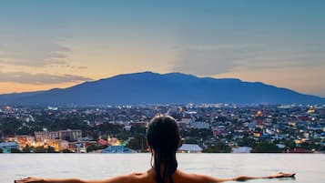 A person in a swimming pool with a cityscape and mountains in the background.