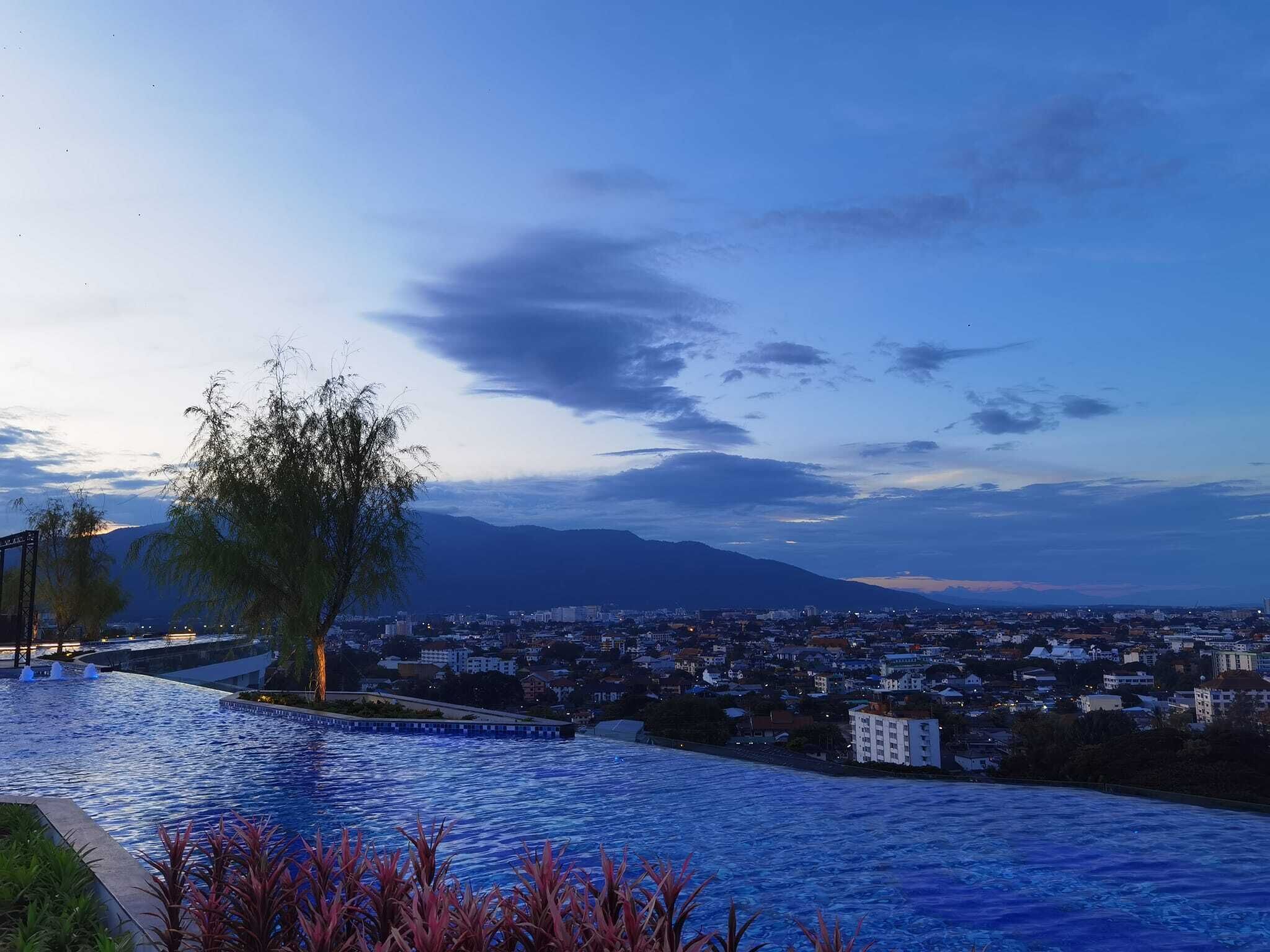 Ein Pool mit Blick auf eine Stadtlandschaft und Berge im Hintergrund.