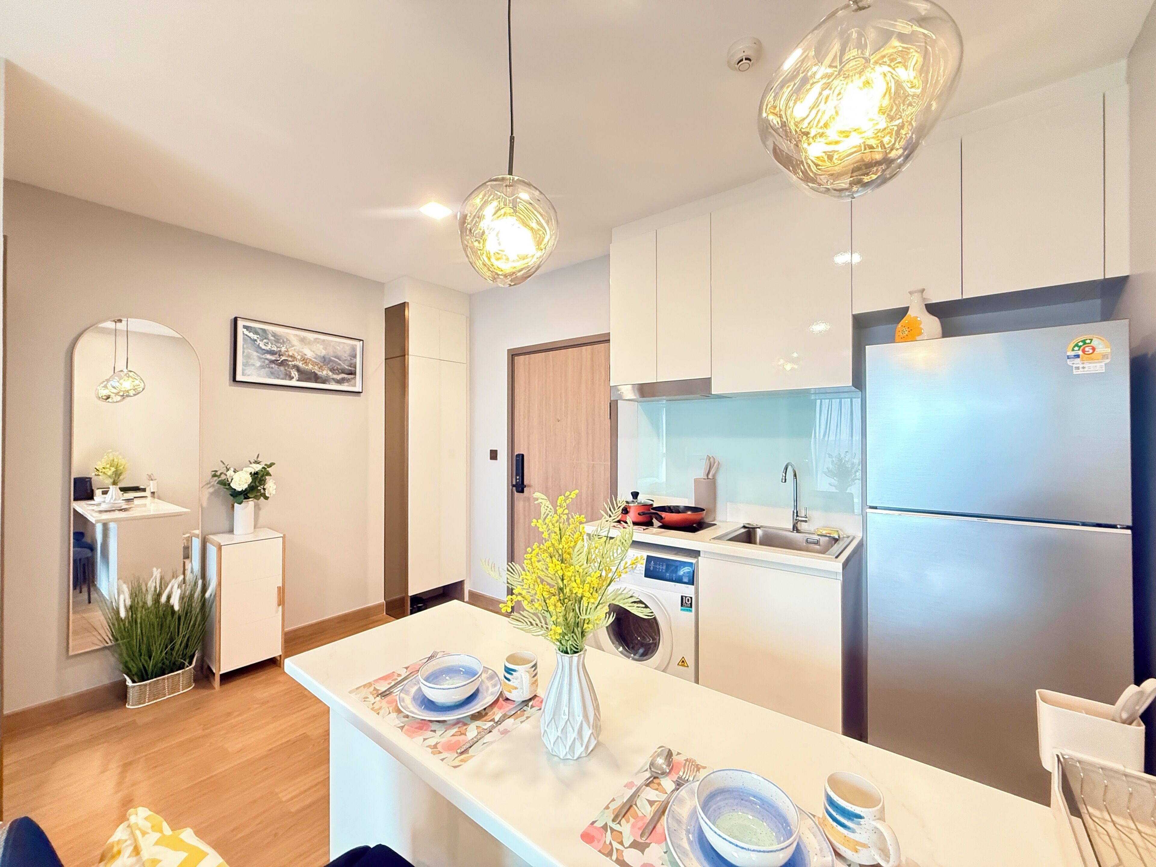 Una cocina moderna con una isla central, electrodomésticos de acero inoxidable e iluminación colgante.