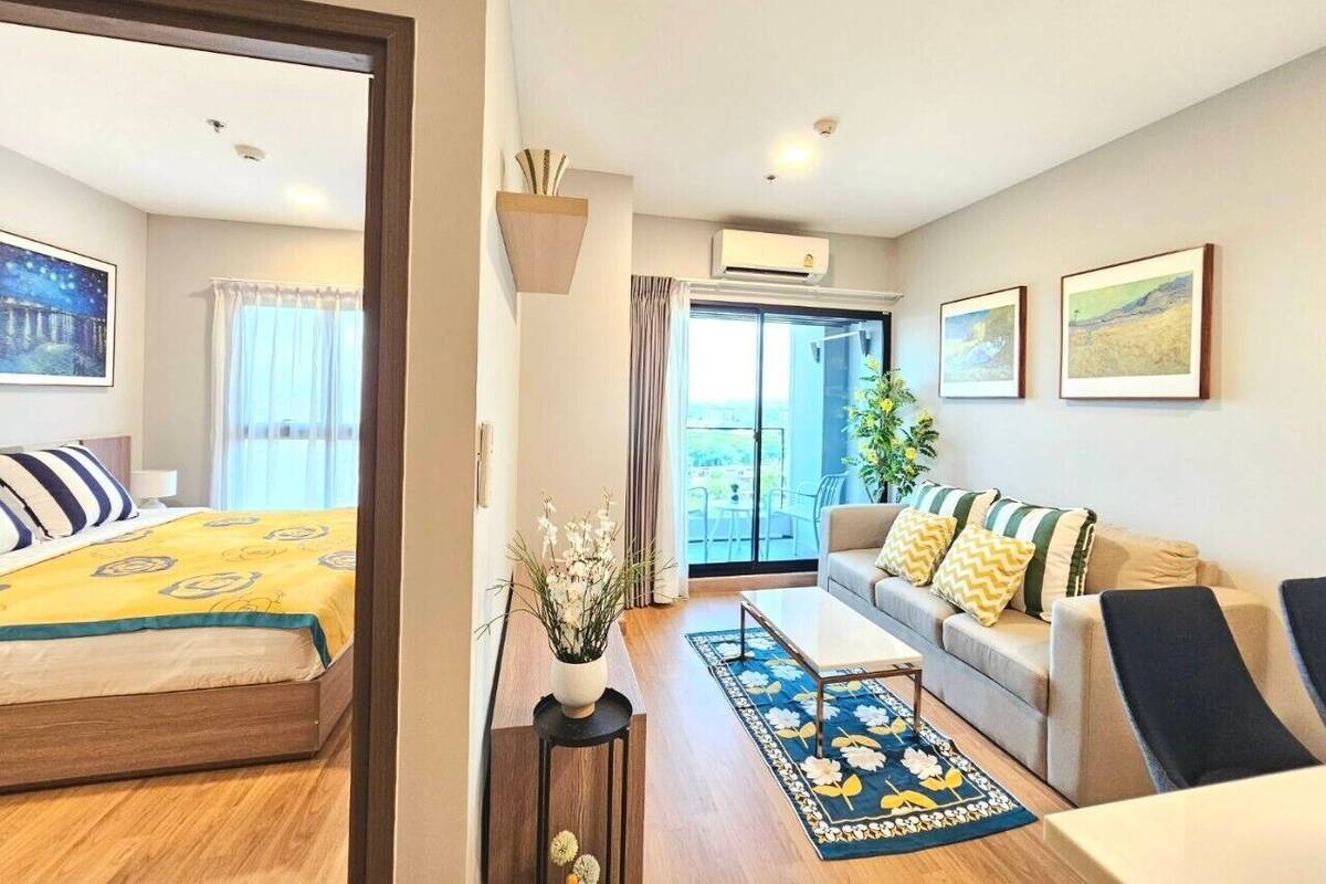 A hotel room with a bed, a sofa, a coffee table, and a view of the outdoors.