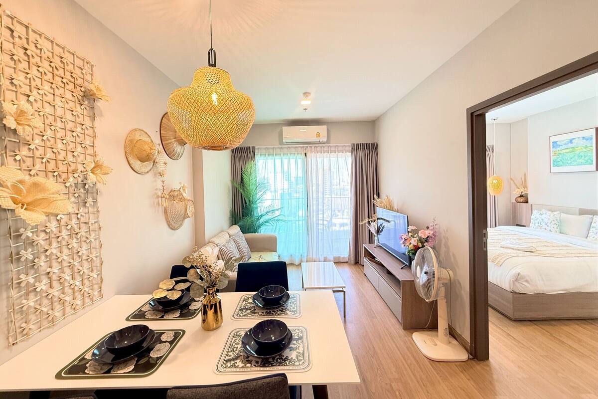 A modern living room with a dining area, a sofa, a TV, and a bed.