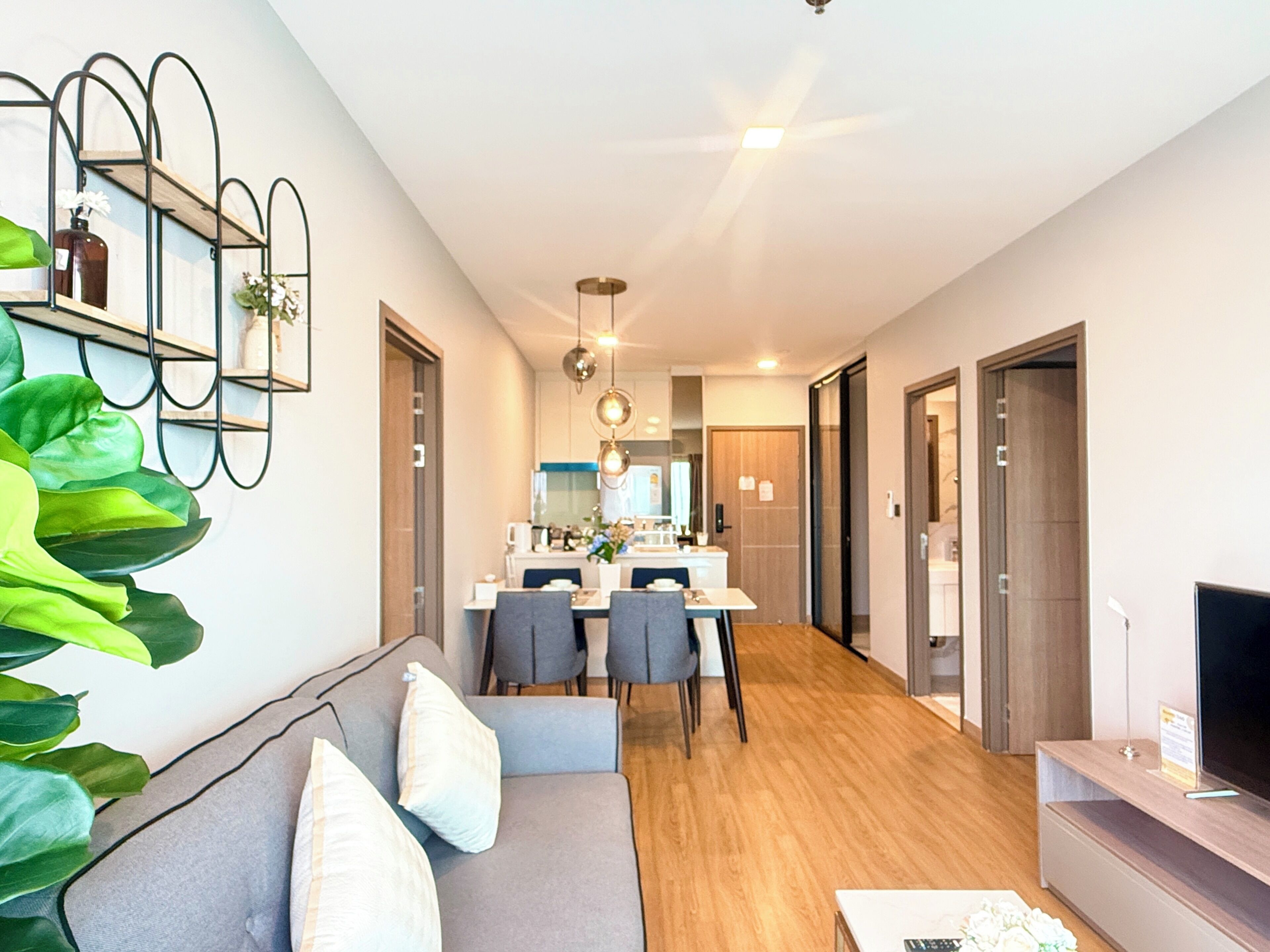 Una sala de estar moderna con un sofá, una mesa de centro y un mueble para televisor. Hay un comedor con sillas y una mesa, y una cocina al fondo.