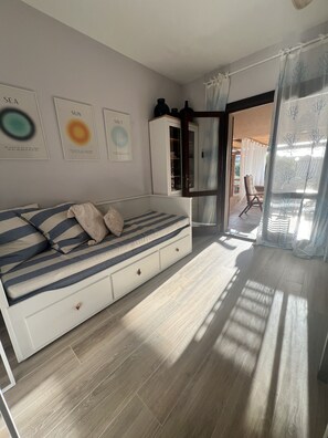Relax in a serene bedroom with a large bed, framed artworks, and a view of the outdoor area.