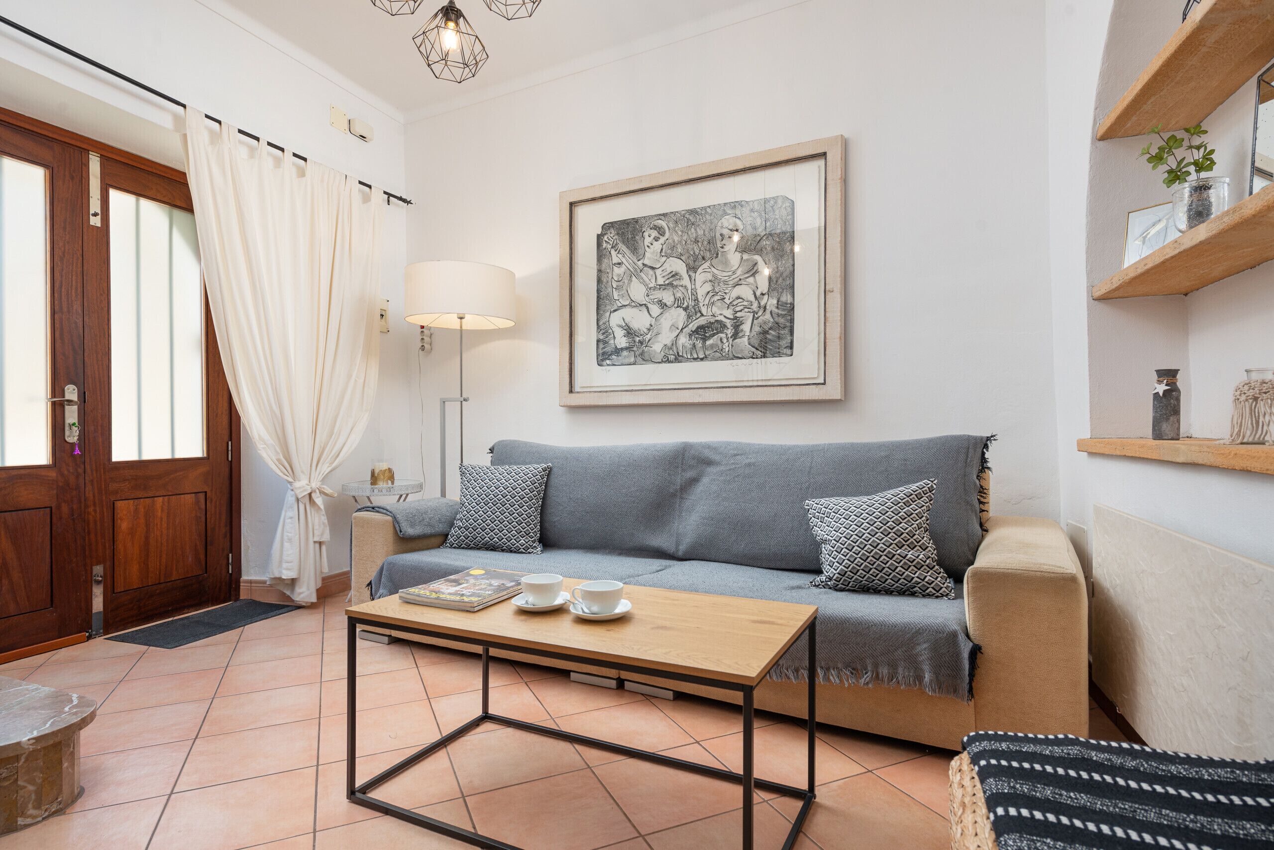 A living room with a sofa, a coffee table, a lamp, and a framed artwork on the wall.