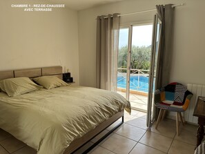 A bedroom with a bed, a nightstand, a chair, and a view of a swimming pool through a sliding door. - 350 m² house with 10 beds and beautiful sea view (Solliès-Ville)