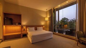 A hotel room with a large bed, a TV, a sofa, and a balcony with a view.