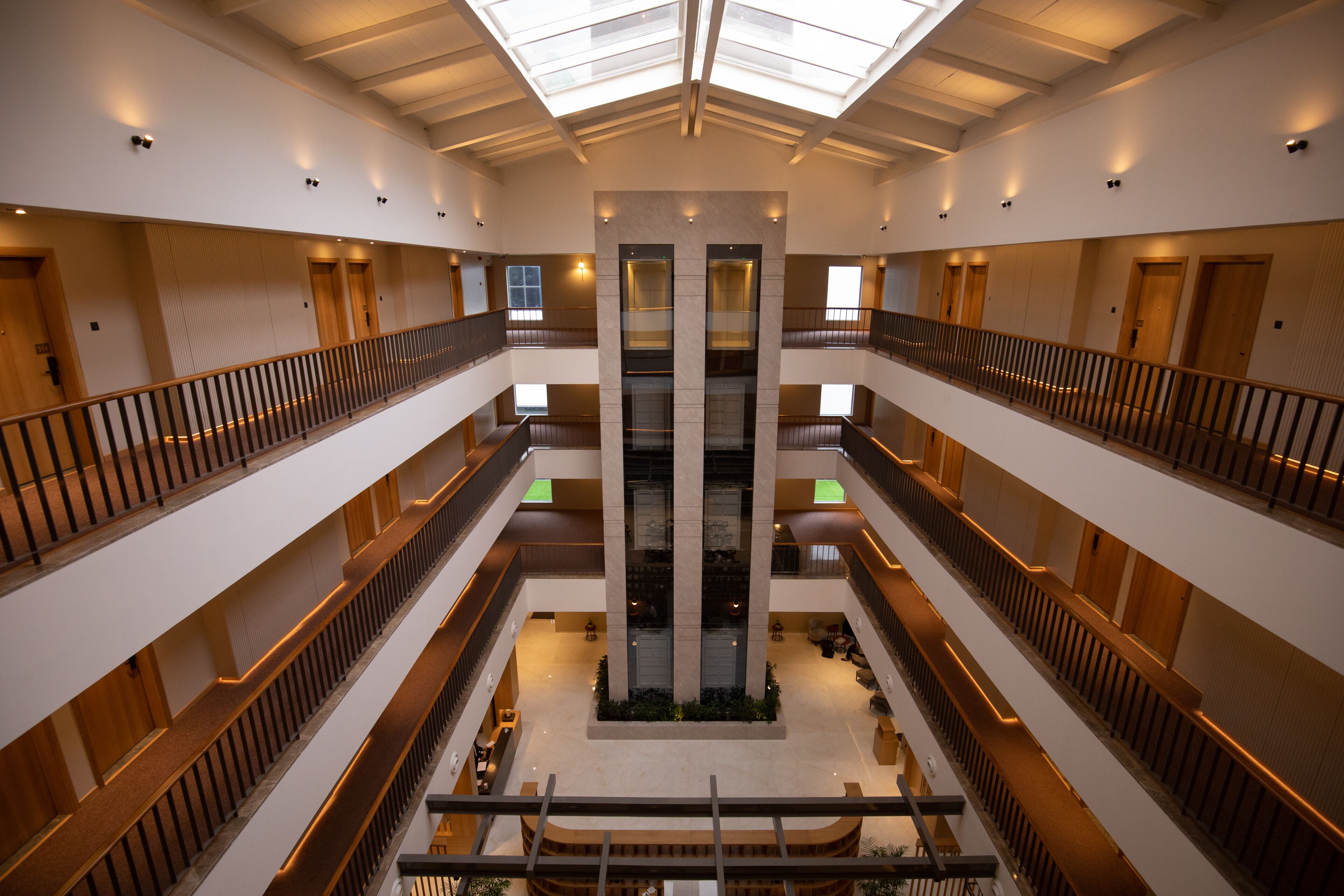 A multi-level atrium with a central staircase, multiple floors, and a glass ceiling.