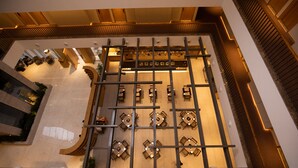 Un moderno vestíbulo de hotel con un área de descanso central y una escalera que conduce a los pisos superiores.