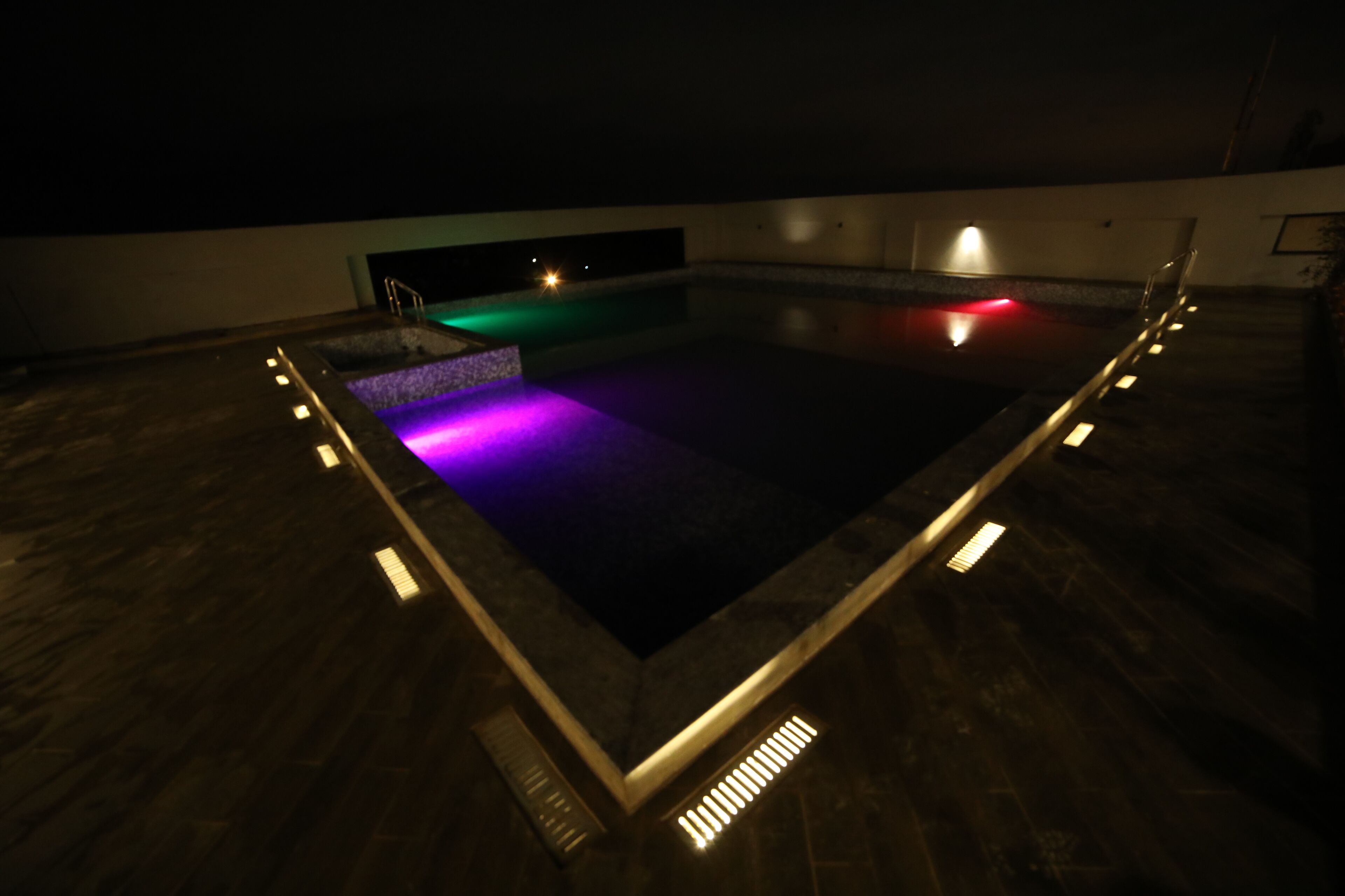 Piscina rectangular con interior oscuro y bordes iluminados.