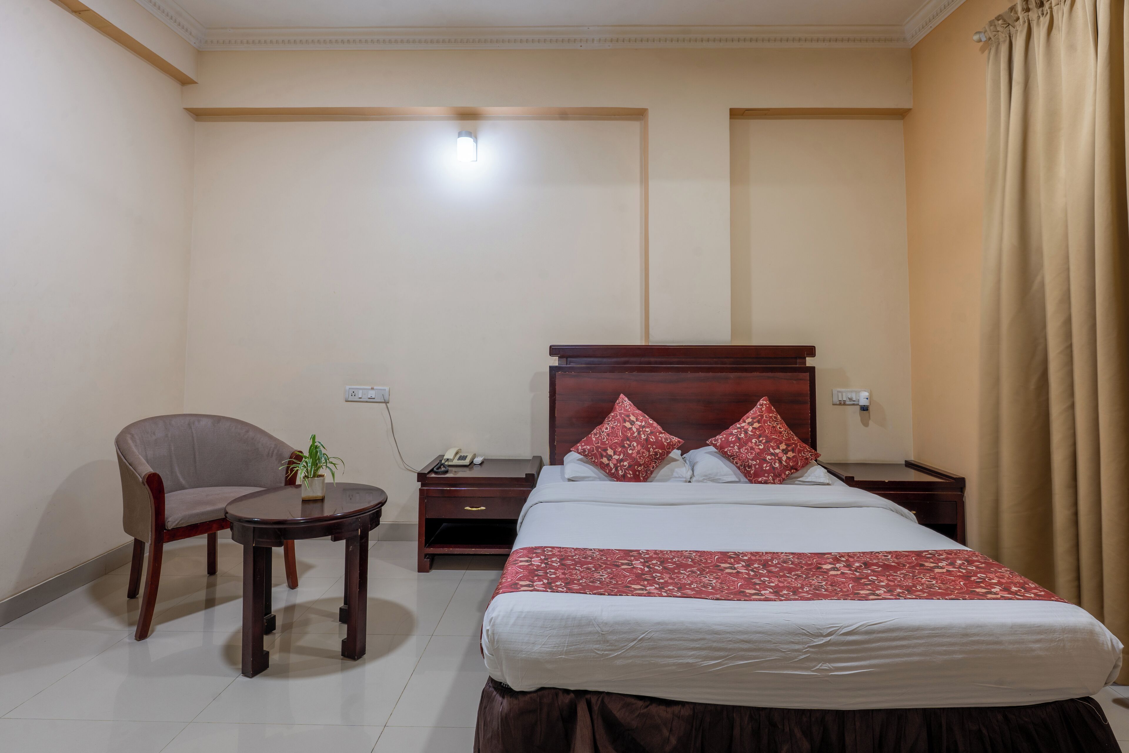 A hotel room with a bed, a chair, a small table, and a nightstand.