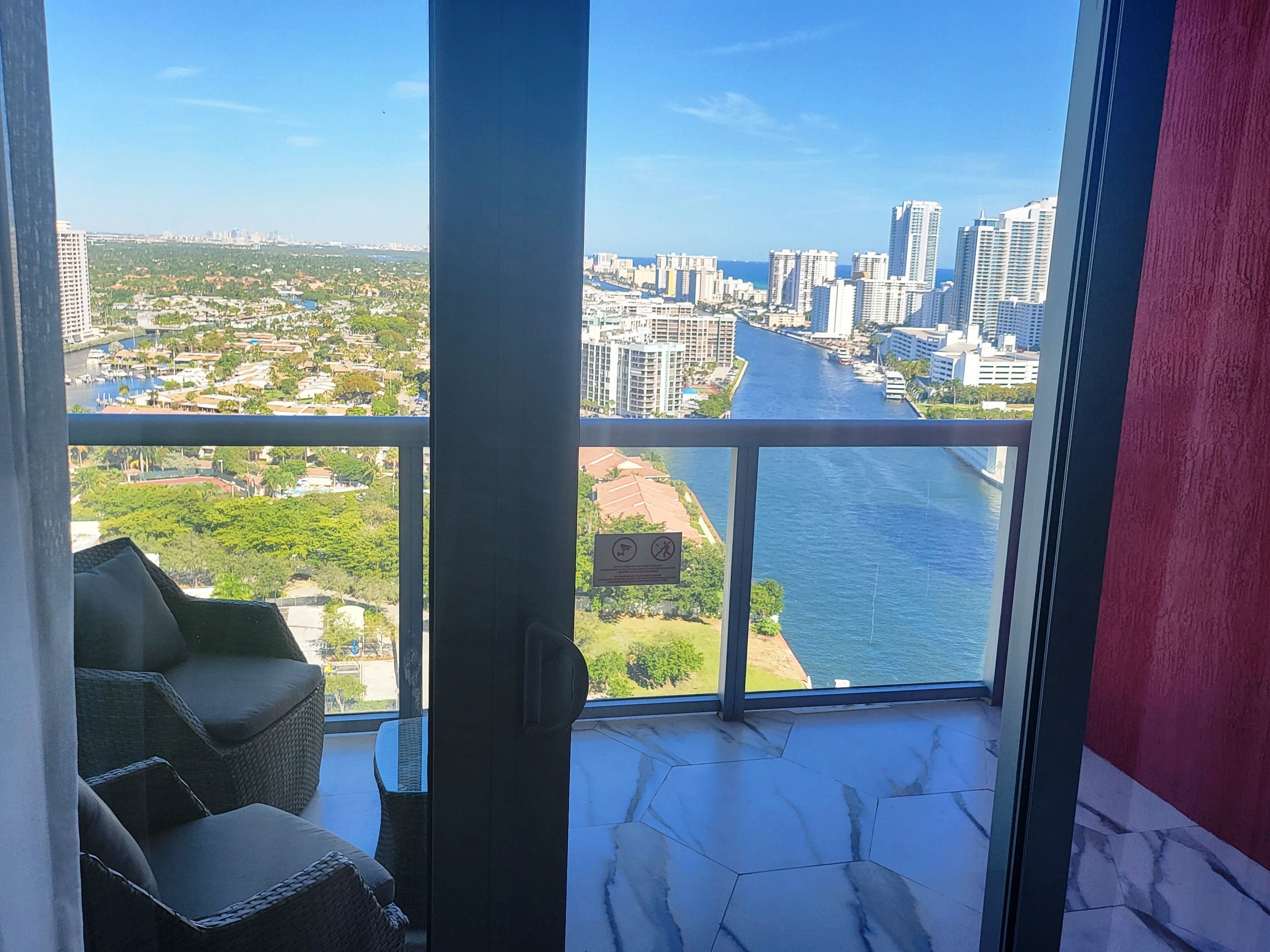 A balcony with a view of a river and cityscape, including high-rise buildings and greenery.