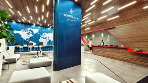 Een moderne lobby met een blauwe wand met een wereldkaart, een receptiebalie en een trap.