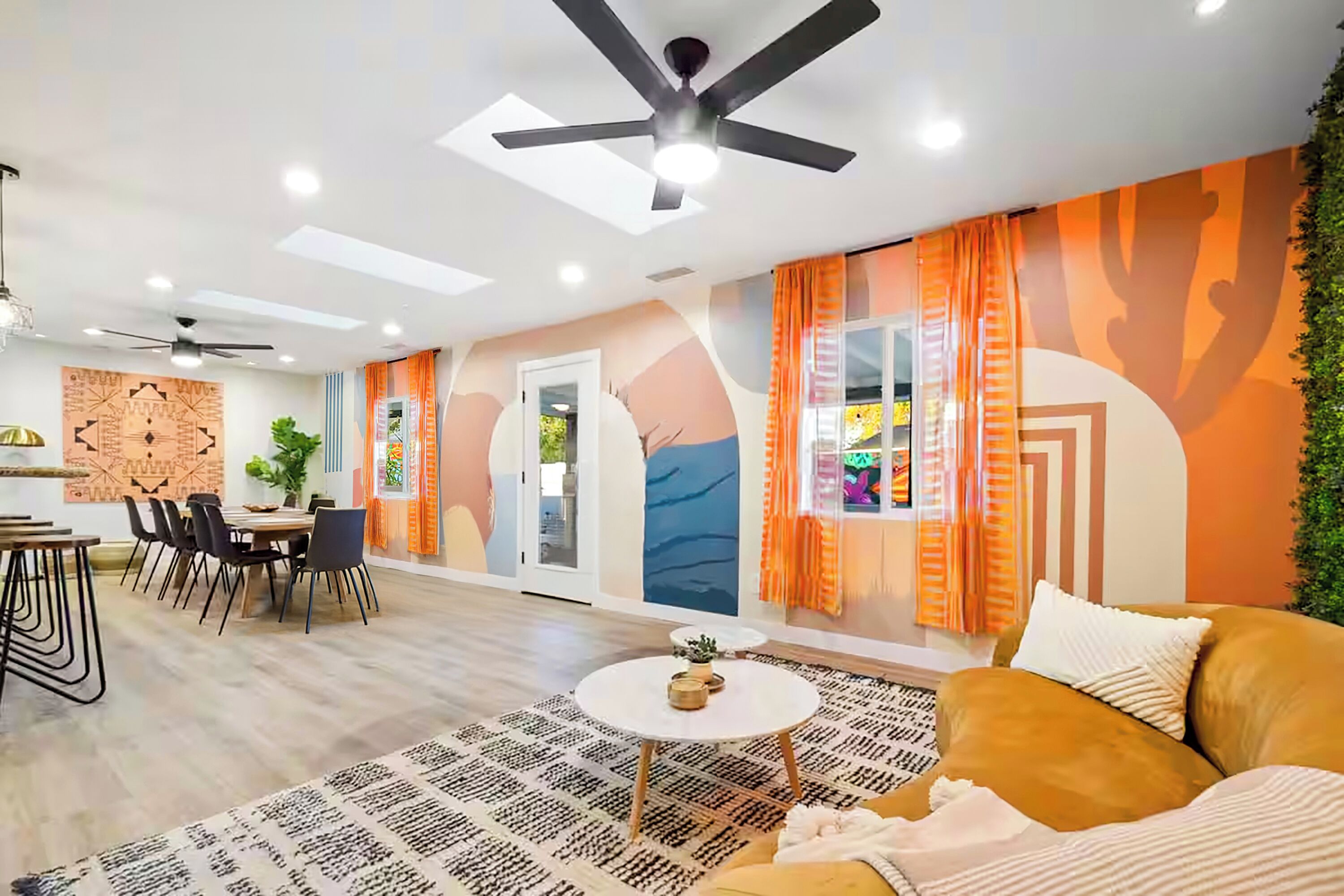 A modern living room with a dining area, featuring a ceiling fan, a round coffee table, and a sofa.