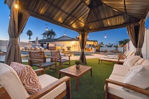 An outdoor lounge area with wooden furniture, a pool, and a covered seating area. - Private Resort! Heated Pool, Basketball, Bowling! (Scottsdale)