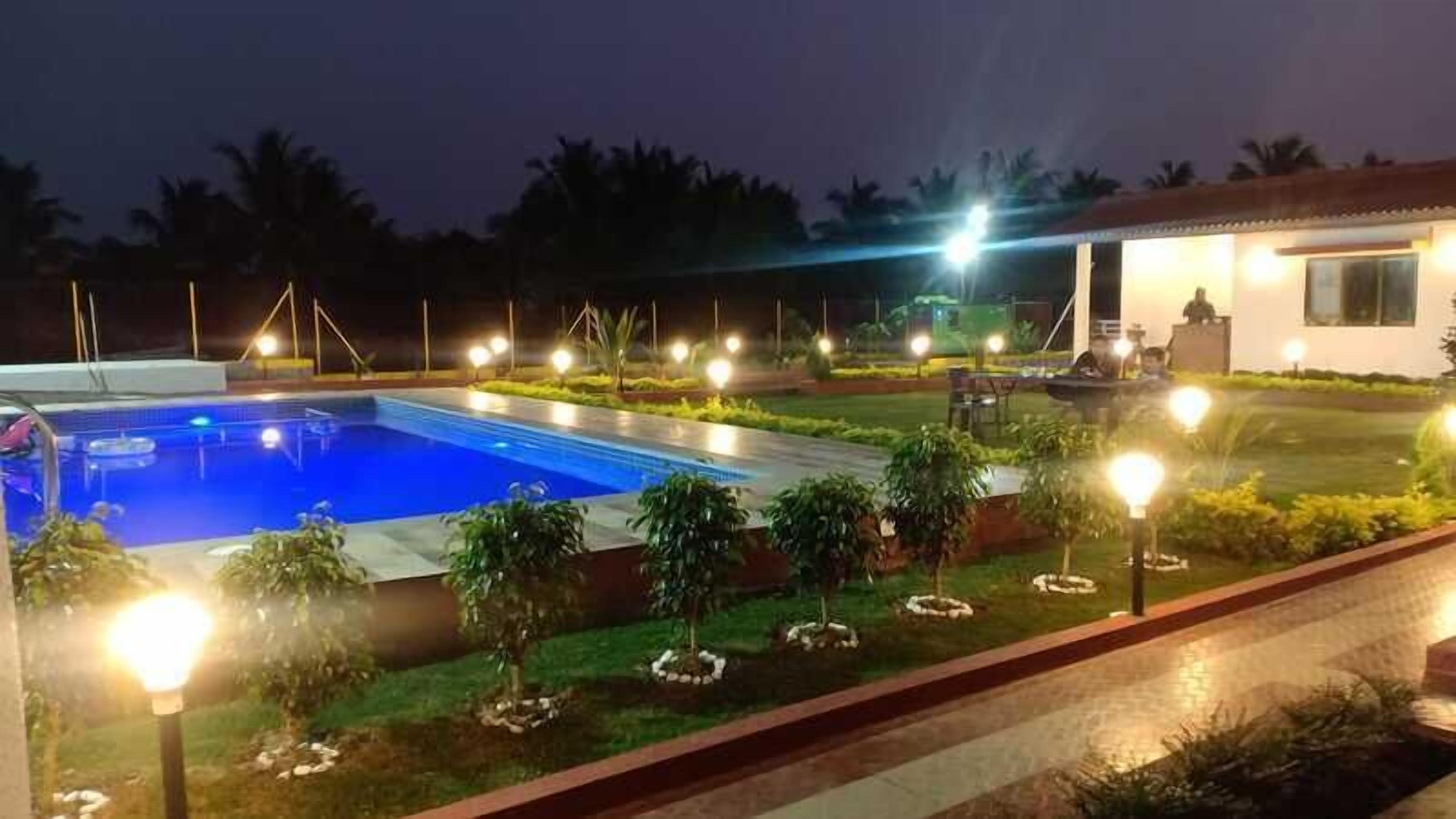 Une piscine entourée de sentiers bien éclairés et de petits arbres, avec un bâtiment en arrière-plan.